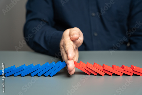 A man stops two domino chains from colliding. The concept of stopping a conflict and preventing further escalation. Elections and confrontation of the parties. Mentoring. Find points of compromise.