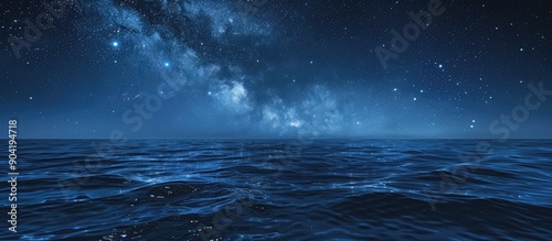 Starry night sky in blue hues above a serene ocean seascape with ample copy space image