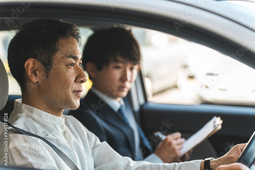 教習所で運転免許を取得するため受講する中年の男性ドライバーと教官の男性 