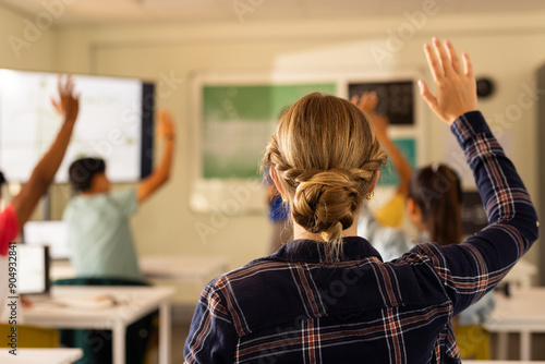 In high school, students raising hands in classroom, actively participating in lesson