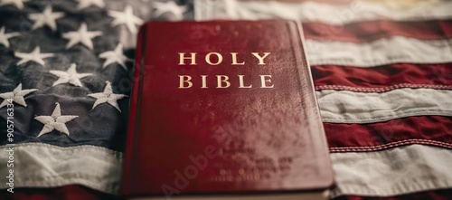 A red holy bible with gold letters rests on the American flag symbolizing faith and patriotism