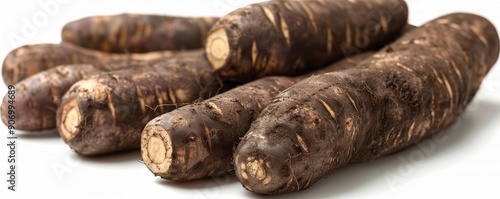 A close-up view of fresh, uncooked cassava roots displayed on a white background, highlighting the texture and natural appearance of this starchy tuber often used in various culinary dishes