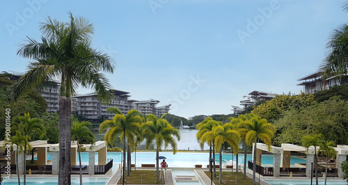 Luxurious Pico de Loro Beach and Country Club: Palm-Fringed Infinity Pool Overlooking Serene Lake with Modern Waterfront Living, Lush Greenery, and Resort-Style Amenities in Batangas, Philippines.