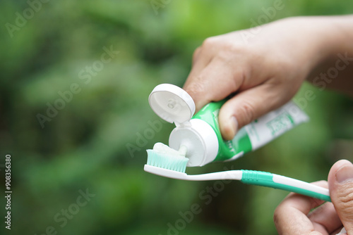 Hand squeezes toothpaste on toothbrush. Concept, dental health care. Brush teeth with fluoride toothpaste for hygiene, clean and strong teeth. Prevention from tooth decay. 