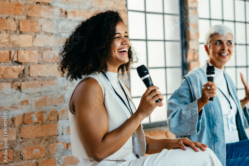 Two excited african-american and caucasian females speaking on a corporate panel discussion