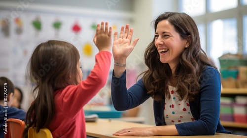 Happy teacher and schoolgirl giving high five during class at school.