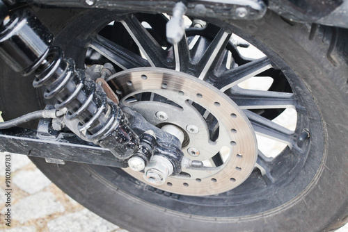 Motorcycle brake disc close-up. Rubber tire and shock absorber. Mud splatters on the wheel, Mechanical part of a vehicle. Mechanism of breaking for safety drive.