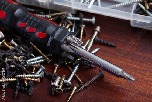 Set of crosshead screwdriver with tip set and fastening devices on wooden background