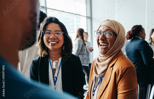 Female colleagues interacting at a corporate workshop with happy smiles and engaging conversations