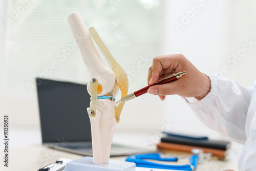 A doctor uses a knee joint model to demonstrate anatomy, diagnose conditions like osteoarthritis, and discuss treatment options, including surgery and therapy, with a patient in a clinical setting.