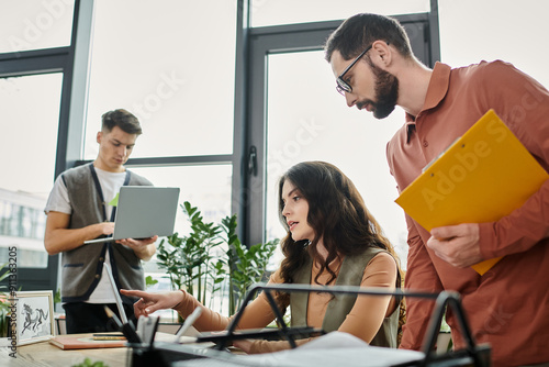 Three coworkers collaborate thoughtfully at their workplace.