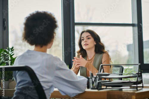 Two colleagues converse about layoffs in a stylish office environment.