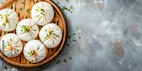 Top view steaming bao buns with chopped scallions in bamboo steamer on gray surface. Banner with copy space