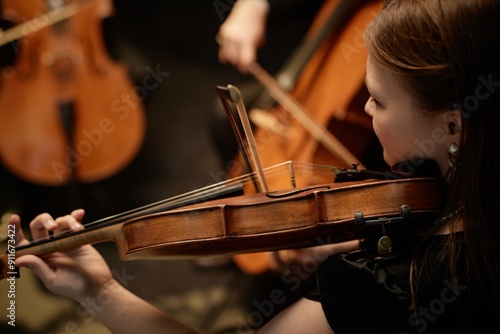 Cropped side view shot of unrecognizable female musician playing violin with string quartet in studio