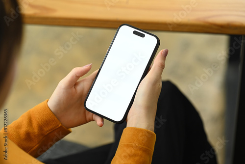 Over the shoulder view of woman holding smartphone with blank screen