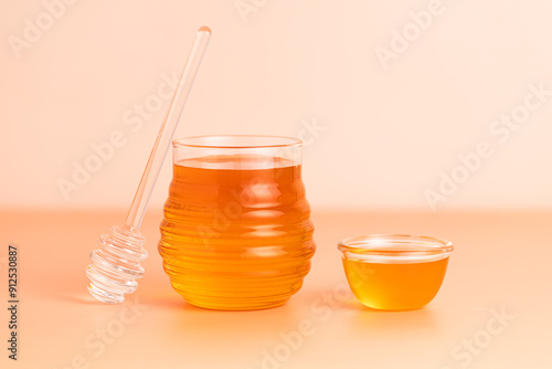 Honey in a glass transparent jar. Beige background.