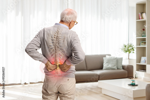 Rear view shot of an elderly man in pain holding his lower back