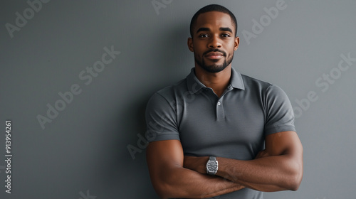 A confident man in a fitted polo shirt, leaning against a wall, posing against a plain grey background , business leader, confidence,