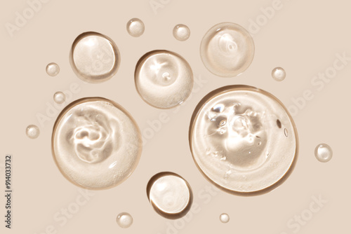 Pure transparent cosmetic gel drops on beige background, skin care glycerin texture. top view.