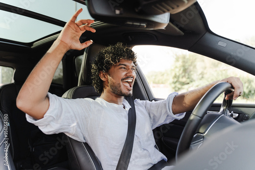 Happy Indian man driving car and singing along to music