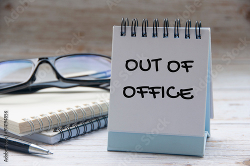 Out of office text on white notepad with notes and glasses background