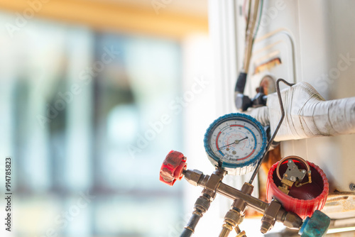 HVAC service technician using manifold gauge to check refrigerant, Air Conditioning Repair.