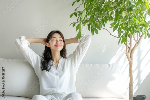 A Japanese woman relaxing on a white sofa, stretching with a smile, indoor plant background. High-resolution, detailed textures, crisp focus