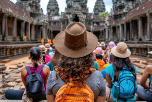 A group of tourists attentively listening to a guide in an ancient temple complex surrounded by stone towers, indicating a sense of cultural immersion and historical learning.