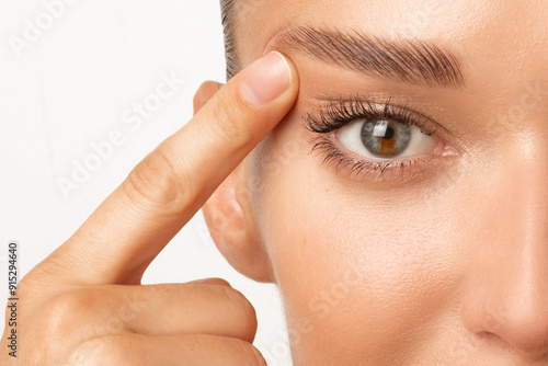 Blepharoplasty. Woman with unusual eye color touching eyelid skin and pointing to the wrinkles on the upper eyelid, closeup shot