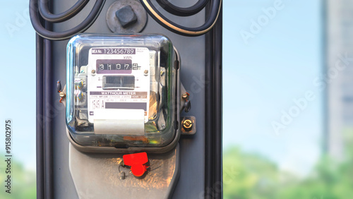 Electricity meter on electric power pole with cable line and blurred outdoor background, close up with copy space, The meter number is a suppose number.