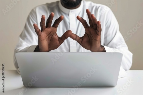 Man Sitting at Desk with Laptop, Hands Open, Minimalist White Background.