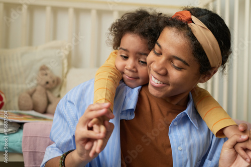 Happy moment featuring African American mother hugging young daughter in comfortable bedroom setting creating a warm and nurturing environment full of love and affection