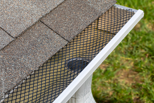 Installing gutter guard mesh screen on rain guttering. Home maintenance, yardwork and roof damage concept