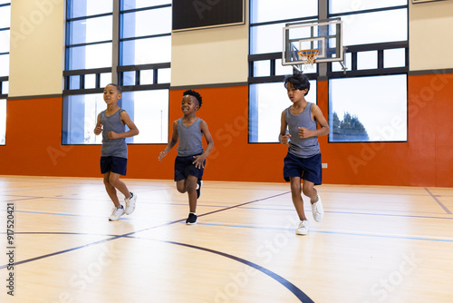 Running in gym, three boys exercising together in school sports class