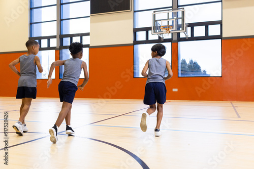 Running in gym, three boys exercising during school physical education class