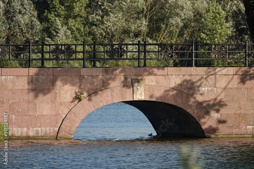 A medieval bridge over a moat of water is the only way into the castle. A duck swims under the bridge.