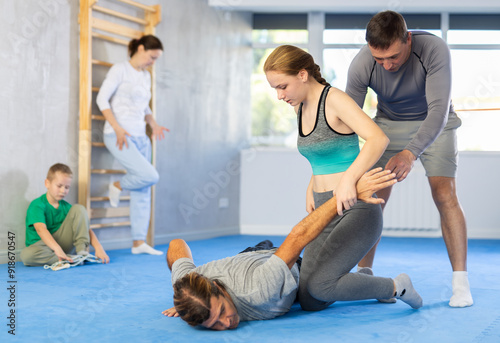 During self-defense training, man coach helps teen girl student complete exercise, neutralize enemy, correctly perform action and defensive movement