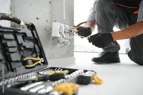 An African electrician installs electrical outlets at a construction site