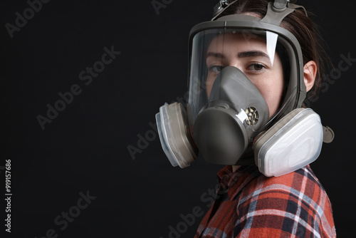 Woman in respirator mask on black background, space for text