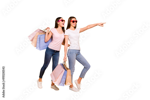 Full length body size view portrait of nice cute charming winsome attractive cheerful straight-haired girls carrying purchase showing far away isolated on bright vivid shine yellow background