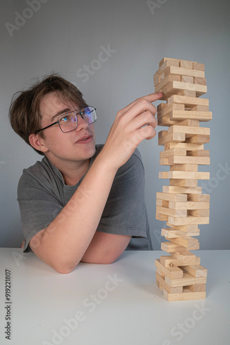 skupiona osoba wyciągająca jedną ręką klocki Jenga