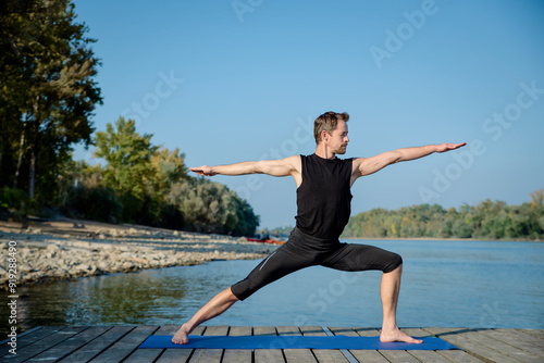 Full length of caucasian man doing yoga on pier by lake