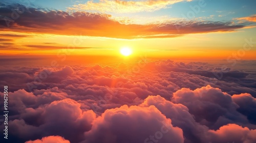 A stunning sunset viewed from above the clouds, with a vibrant orange sky and sunbeams shining through the fluffy, white clouds.