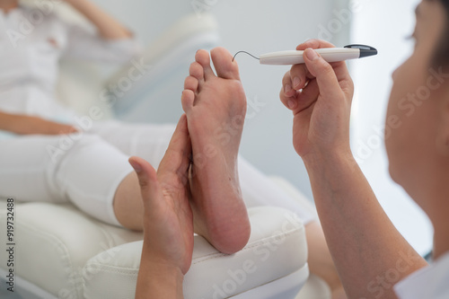 A podologist checks the diabetic foot with a Diabetic Foot Probe. Patient on medical pedicure procedure, visiting podiatrist. Peeling feet. Foot treatment in SPA salon. 