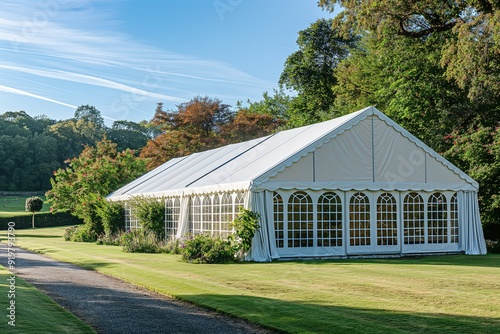 A white wedding marquee with clear windows sits on a grassy lawn.