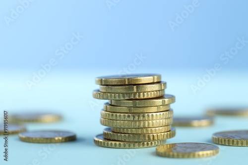 Stack of euro coins on light blue background, closeup