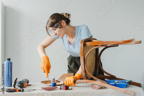 Woman using chisel restoring old wooden chair at home