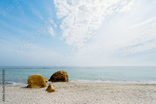 Big stones on the shore of the Black Sea. Yellow stone rocks on a sandy summer beach. Sea view and blue sky with fluffy clouds. Odesa, Ukraine