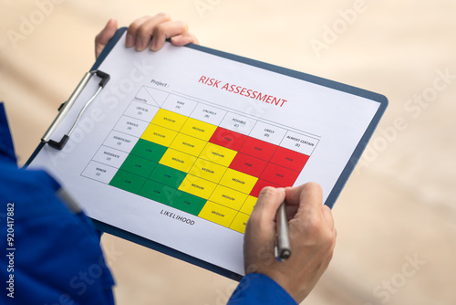 An engineer is using a pen to checking on the safety risk assessment with color matrix form to evaluate the risk level. Industrial ot business working scene, close-up and selective focus.