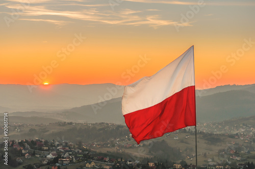 Biało-czerwona flaga Polski na tle zachodzącego słońca w górach - Ochodzita, Koniaków